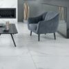 Marmara Blanco Tile installed in a living room, with a gray plush chair and fireplace