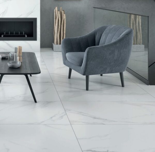 Marmara Blanco Tile installed in a living room, with a gray plush chair and fireplace